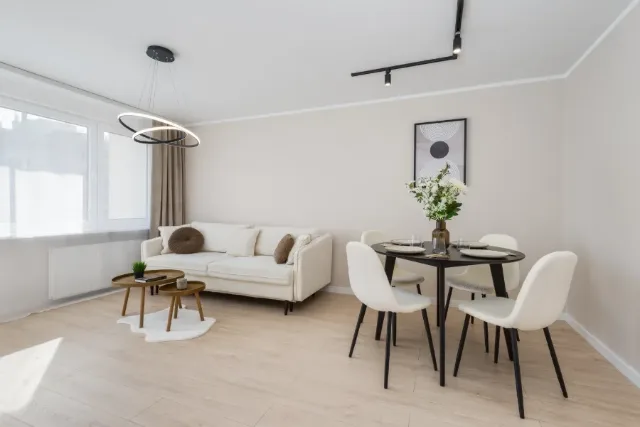 Jasny salon z kremową sofą i okrągłym stołem z czterema krzesłami