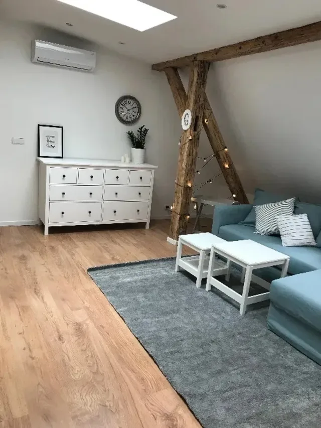 Salon na poddaszu z drewnianą belką i niebieską sofą – zdjęcie przed sesją
